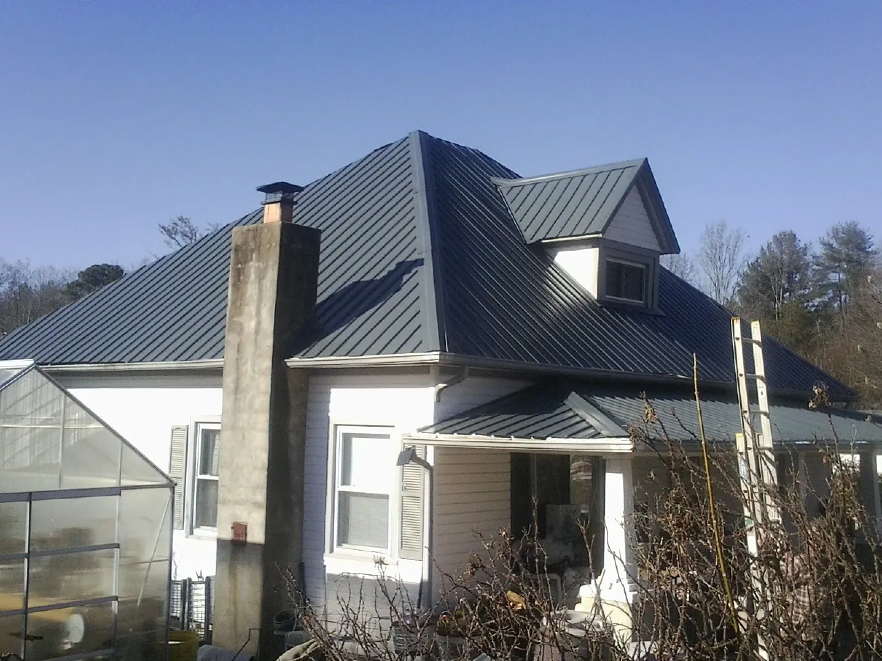 Dark blue standing seam metal roof on a white farmhouse with dormer — Slate & Tile Roof Repair by Roofing Brothers in Juniata