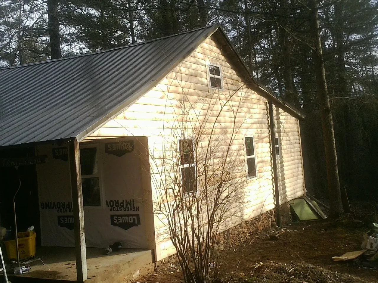 Log siding gable end under a dark metal roof edge in Juniata