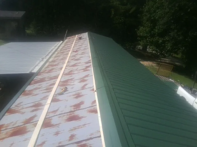 Old rusted panels beside newly installed green metal roofing — Wind Damage Roof Repair by Roofing Brothers in Juniata