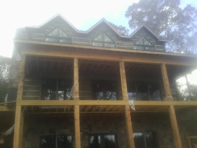 Dormers and porch framing on a large log home under construction — Roof Coating work by our crew in Juniata