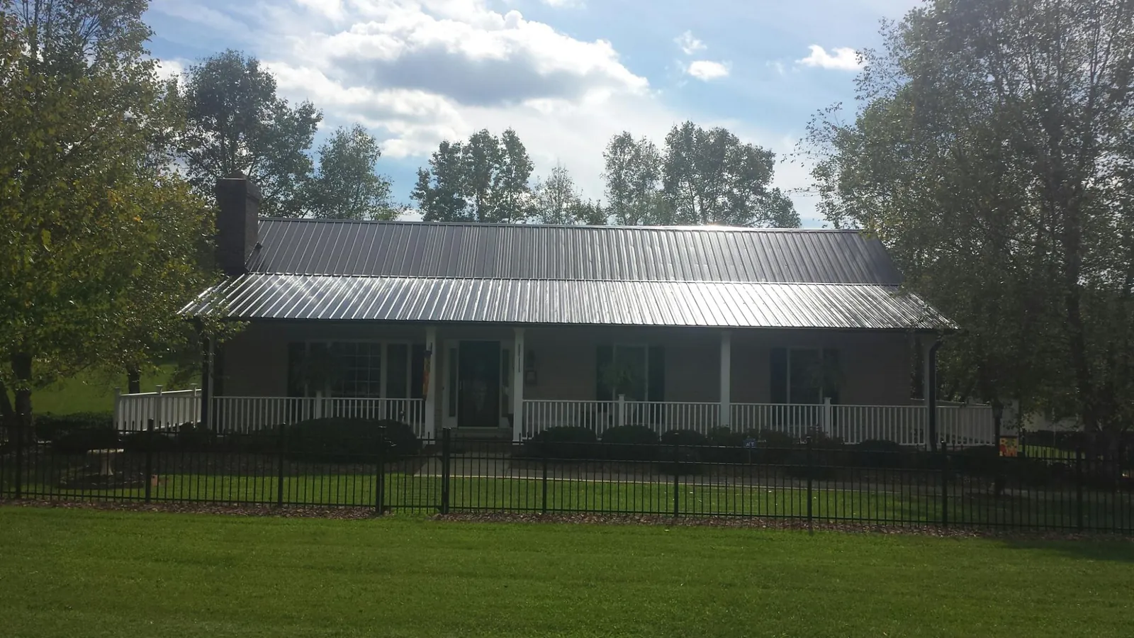 Gray metal roof on a brick ranch with a full width front porch — Gutter Guard Installation work by our crew in Juniata