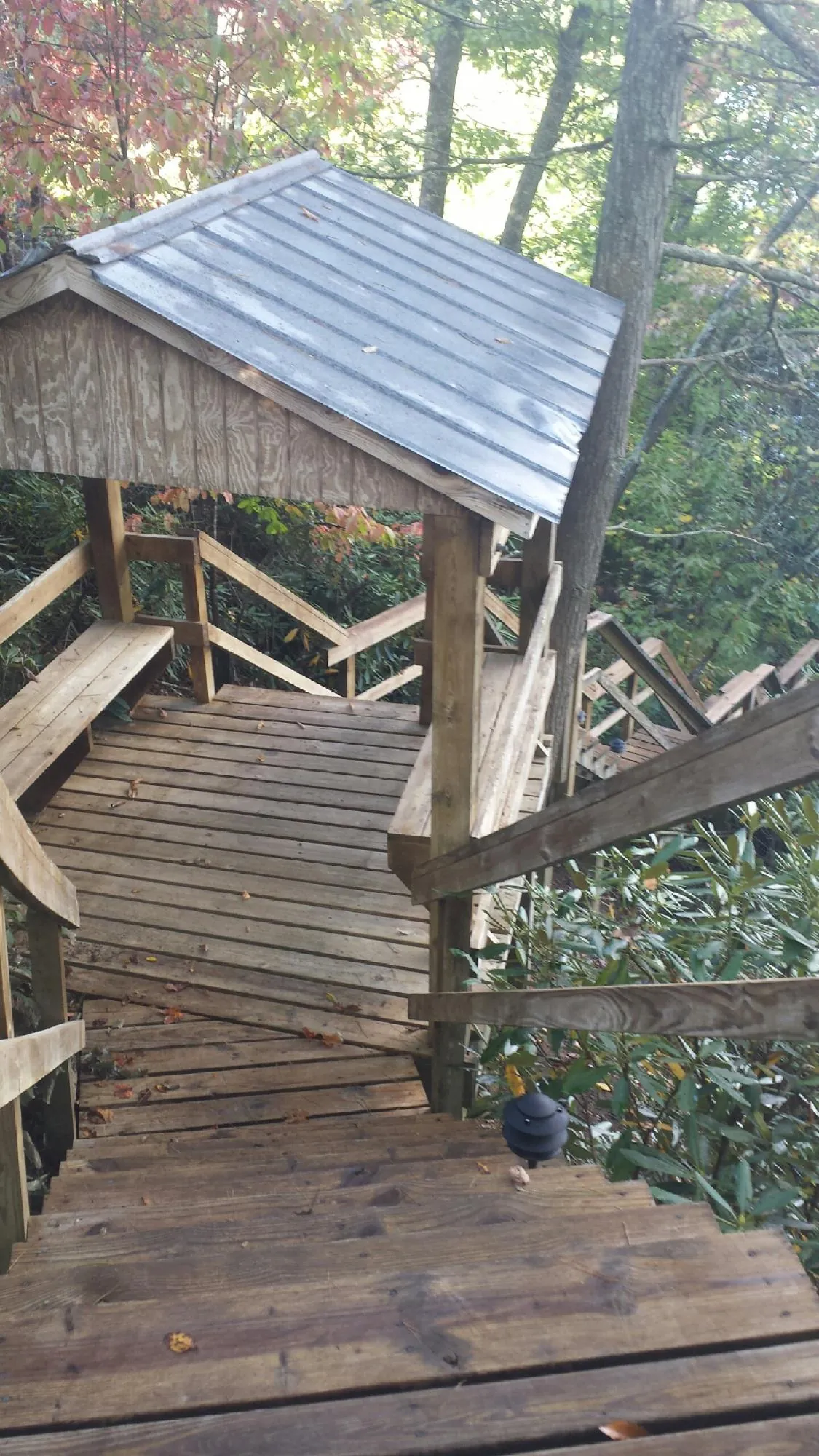 Metal roofed shelter over wooden steps on a wooded walkway — Skylight Repair & Installation work by our crew in Juniata