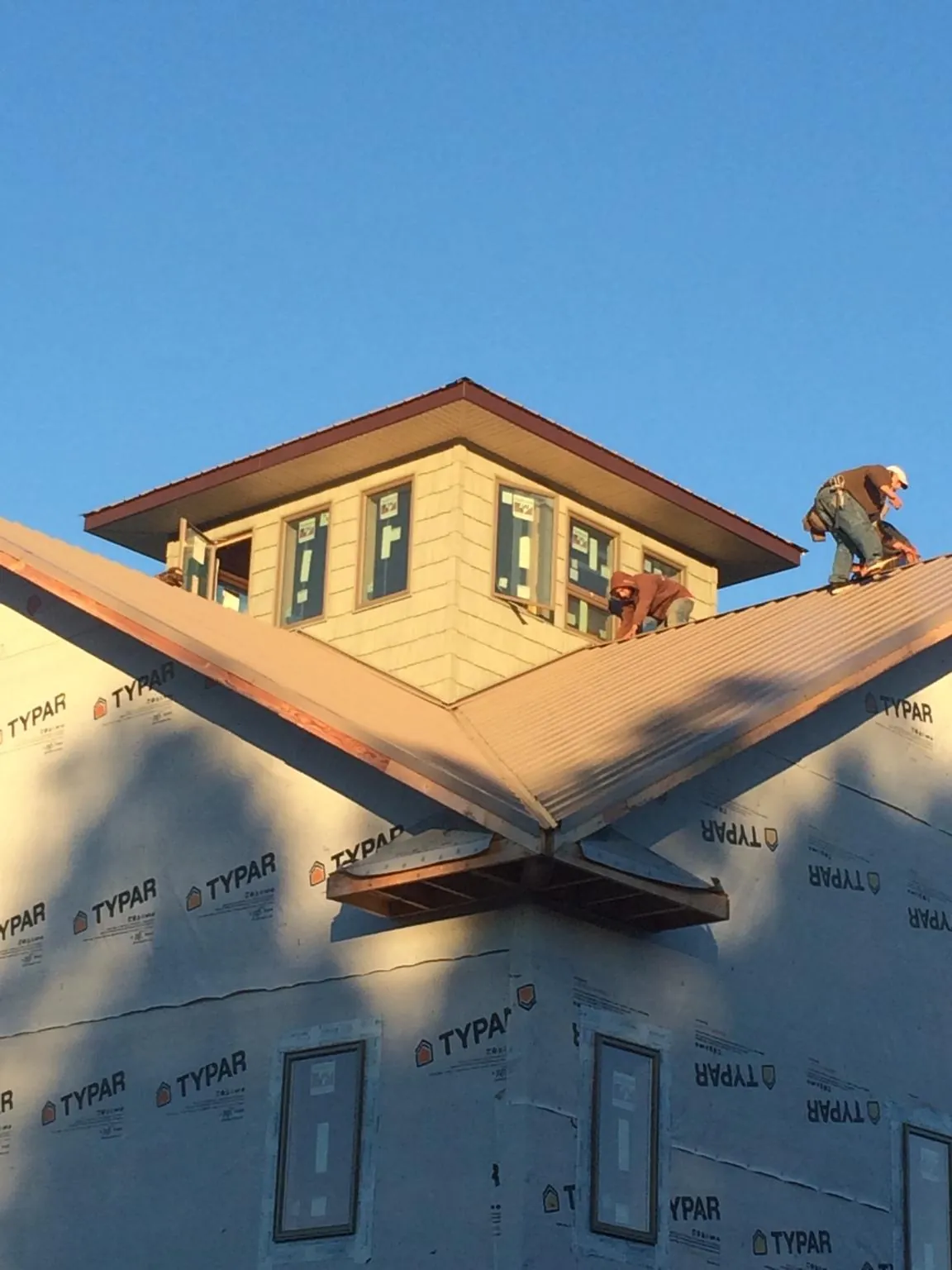 Roofers working around a rooftop cupola on a new metal roof at sunset — Roof Waterproofing in Juniata by Roofing Brothers